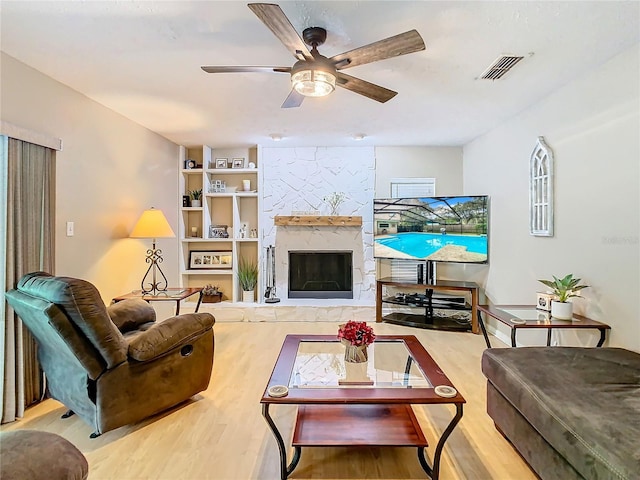 living room featuring ceiling fan, hardwood / wood-style flooring, and a fireplace