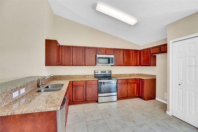 kitchen featuring vaulted ceiling, light stone countertops, light tile patterned floors, stainless steel appliances, and sink