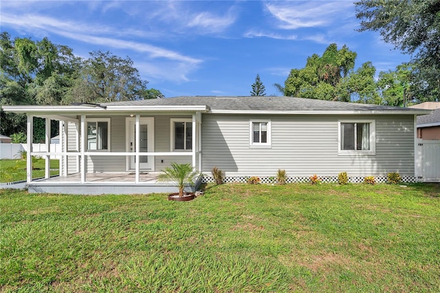 rear view of house featuring a lawn and a porch