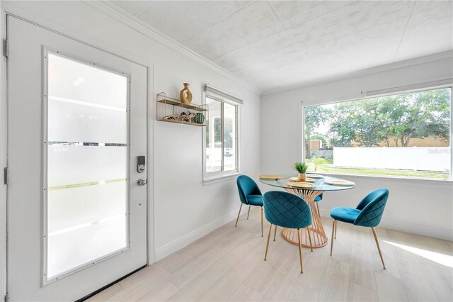 dining area featuring light hardwood / wood-style flooring, a wealth of natural light, and ornamental molding