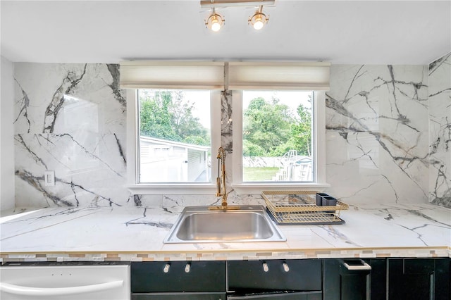 kitchen with backsplash, tile walls, dishwasher, and sink