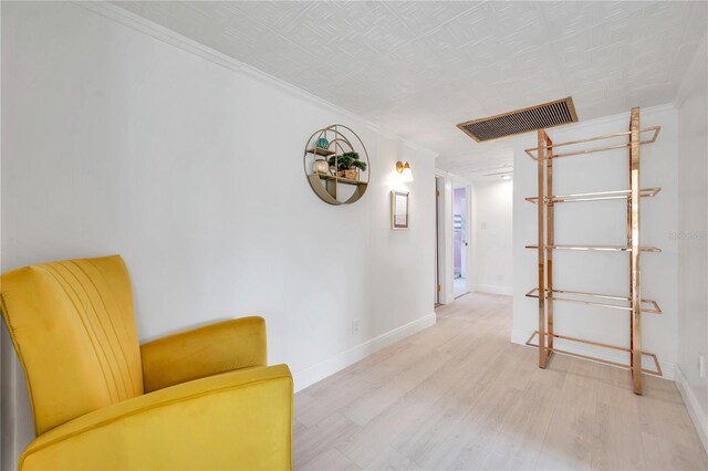 living area featuring light hardwood / wood-style flooring and ornamental molding