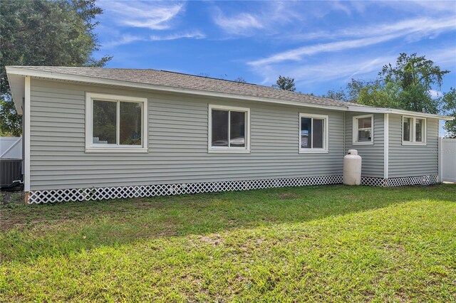 back of house featuring a lawn and central air condition unit