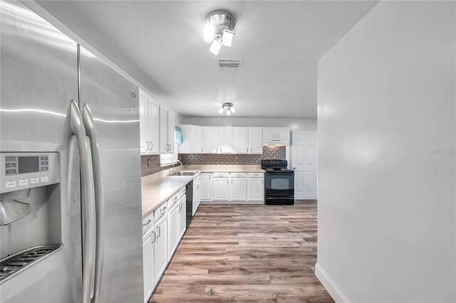 kitchen featuring white cabinets, sink, backsplash, black appliances, and light wood-type flooring