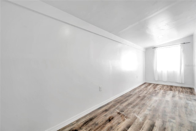 unfurnished room featuring wood-type flooring and vaulted ceiling