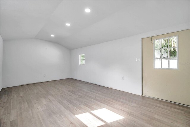 spare room featuring light hardwood / wood-style floors and vaulted ceiling