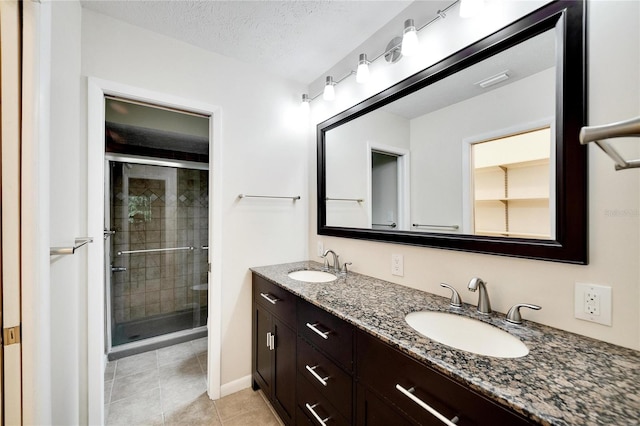 bathroom with tile patterned flooring, a textured ceiling, a shower with door, and vanity