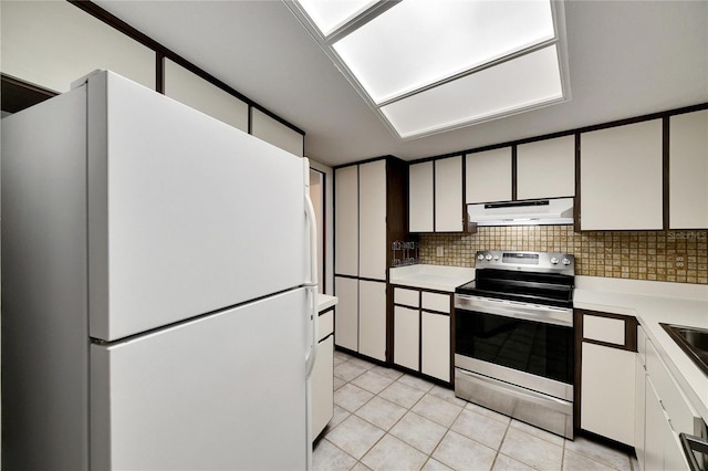 kitchen with white refrigerator, electric range, white cabinetry, decorative backsplash, and light tile patterned floors