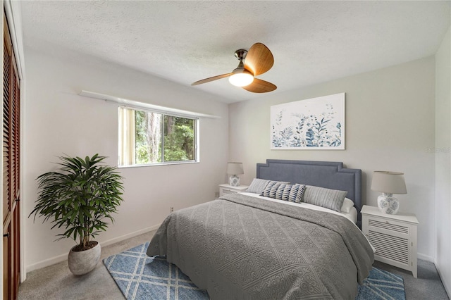 bedroom with ceiling fan, carpet floors, and a textured ceiling