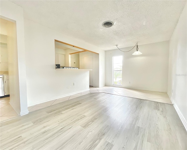 empty room with light wood-type flooring and a textured ceiling