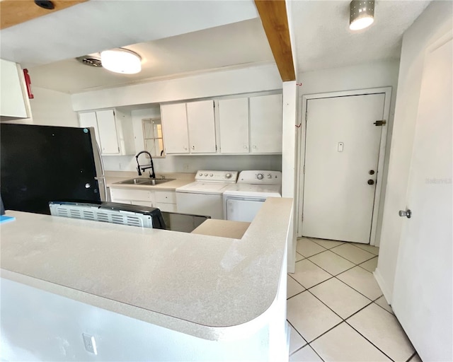 kitchen featuring white cabinets, light tile patterned floors, sink, independent washer and dryer, and black refrigerator