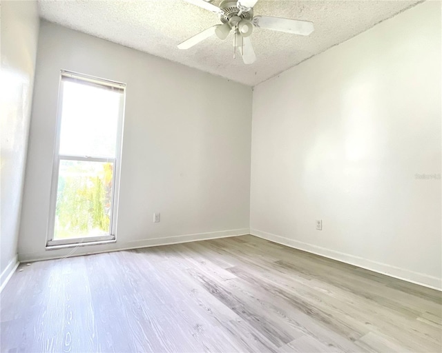 empty room featuring light wood-type flooring, a textured ceiling, and ceiling fan