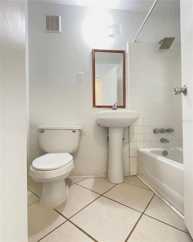 bathroom with tiled shower / bath combo, toilet, and tile patterned floors