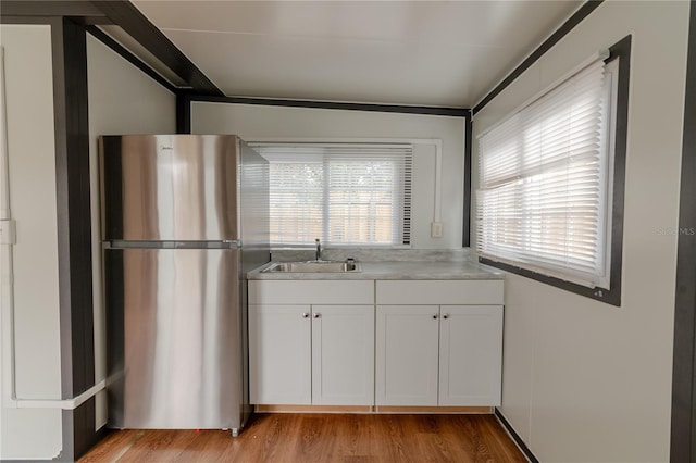 kitchen featuring white cabinetry, stainless steel refrigerator, a wealth of natural light, and sink