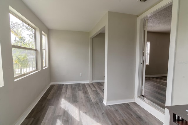 empty room with a textured ceiling and light hardwood / wood-style flooring