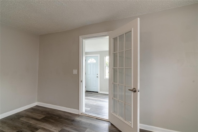 empty room with dark wood-type flooring and a textured ceiling