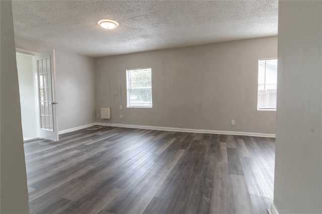 empty room with a textured ceiling and dark hardwood / wood-style floors