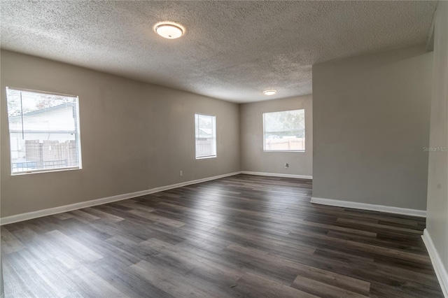 spare room featuring a textured ceiling, plenty of natural light, and dark hardwood / wood-style floors