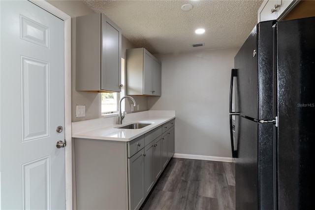 kitchen with black refrigerator, gray cabinetry, a textured ceiling, sink, and dark hardwood / wood-style floors