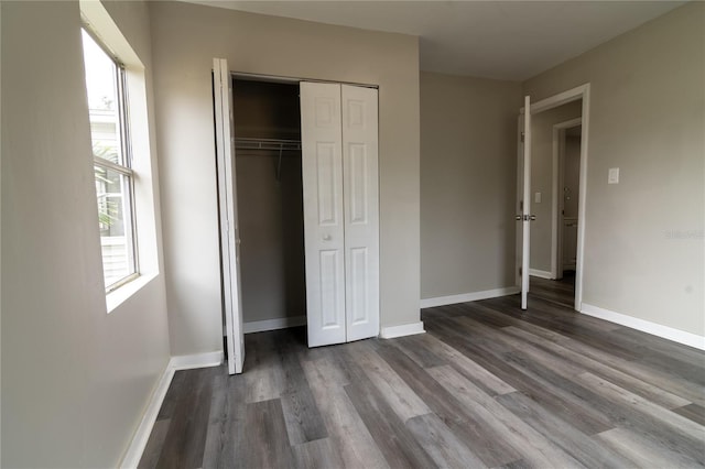 unfurnished bedroom with a closet, hardwood / wood-style flooring, and multiple windows