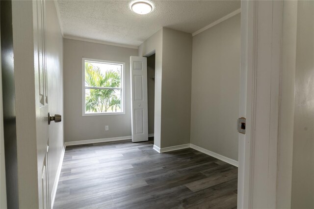 spare room featuring dark wood-type flooring, a textured ceiling, and ornamental molding