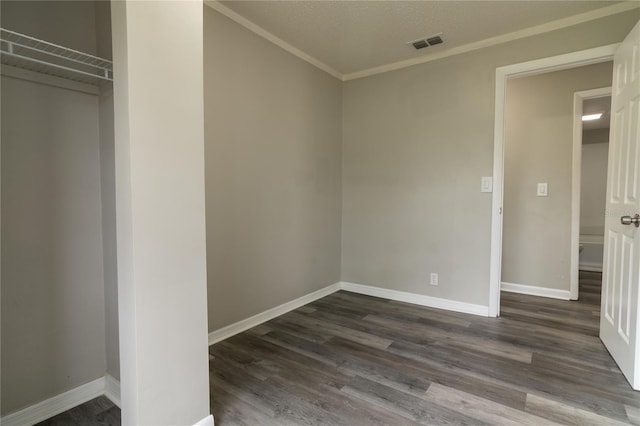 unfurnished bedroom with a textured ceiling, dark hardwood / wood-style flooring, a closet, and ornamental molding