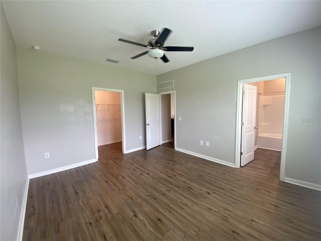 unfurnished bedroom featuring dark hardwood / wood-style floors, a spacious closet, ceiling fan, and a closet