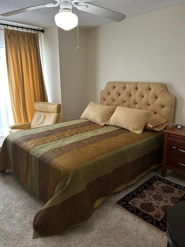 carpeted bedroom featuring ceiling fan and a textured ceiling