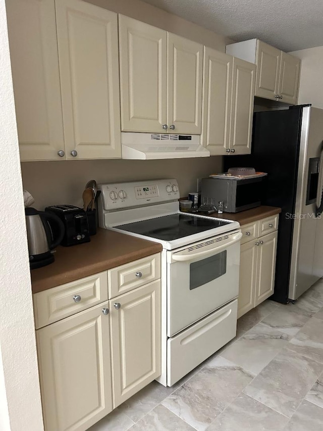 kitchen with appliances with stainless steel finishes, cream cabinetry, and a textured ceiling