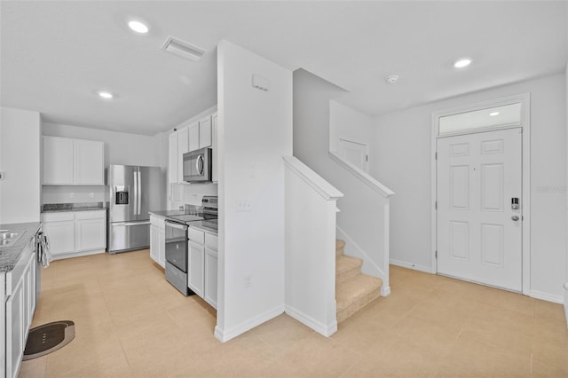 kitchen featuring stainless steel appliances, light tile patterned flooring, and white cabinetry