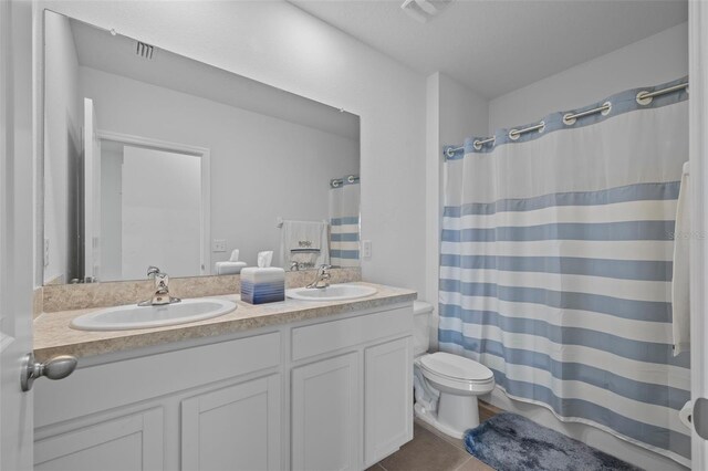 bathroom with a shower with curtain, tile patterned floors, vanity, and toilet