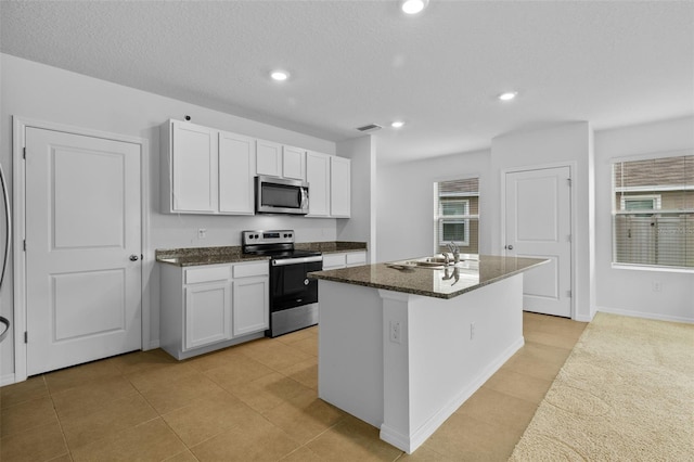 kitchen featuring white cabinets, sink, a textured ceiling, a center island with sink, and stainless steel appliances