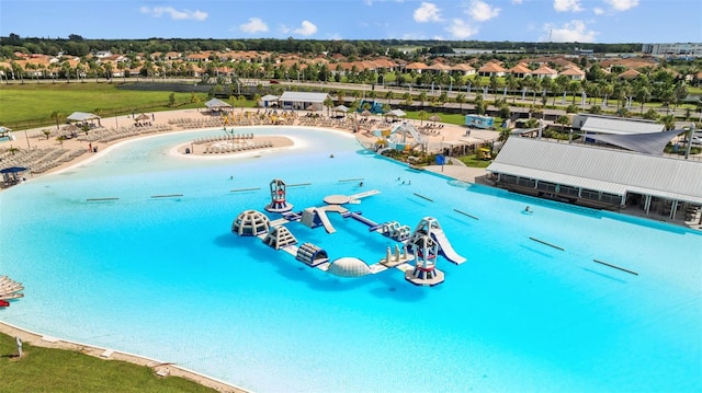 view of swimming pool with a water slide, a beach view, and a water view