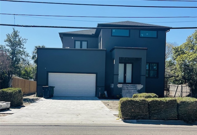 view of front of home featuring decorative driveway, french doors, stucco siding, an attached garage, and fence