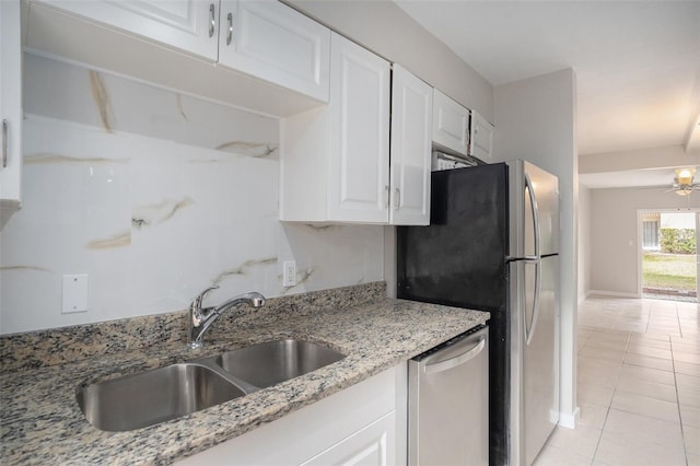 kitchen with appliances with stainless steel finishes, white cabinetry, light stone counters, ceiling fan, and sink