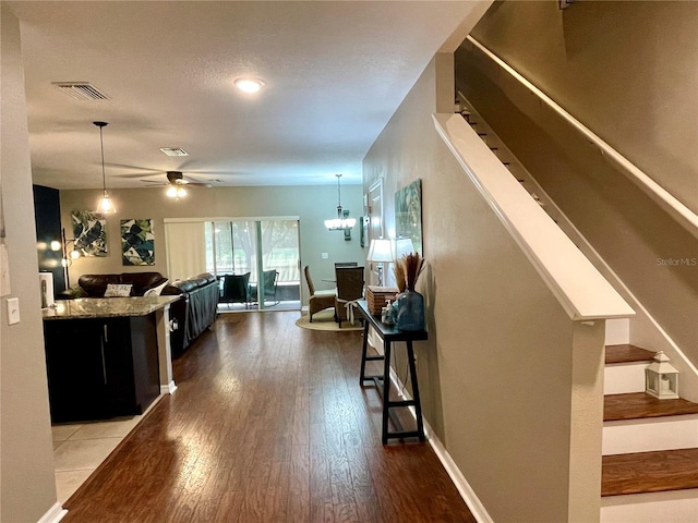 interior space featuring a breakfast bar area, ceiling fan with notable chandelier, hanging light fixtures, and hardwood / wood-style floors