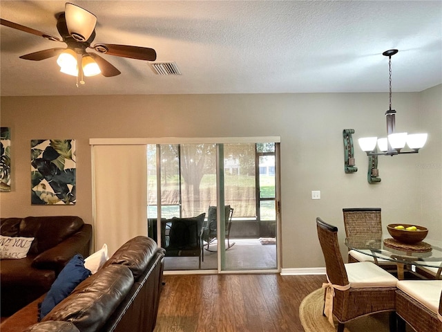 dining space with ceiling fan with notable chandelier, a textured ceiling, and dark wood-type flooring