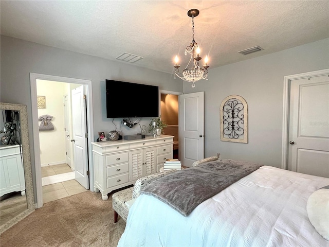 bedroom with light carpet, a textured ceiling, ensuite bath, and an inviting chandelier