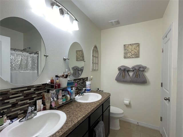 bathroom with a textured ceiling, tasteful backsplash, tile patterned floors, vanity, and toilet