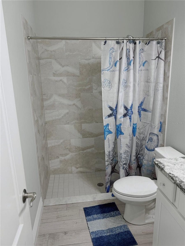 bathroom with hardwood / wood-style floors, walk in shower, vanity, and toilet