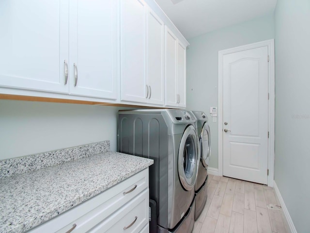 washroom with light hardwood / wood-style flooring, cabinets, and washing machine and dryer