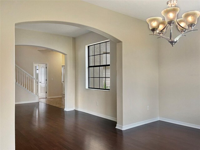 empty room featuring dark hardwood / wood-style floors and a notable chandelier