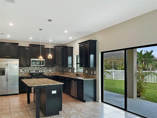 kitchen with sink, a kitchen island, decorative light fixtures, stainless steel appliances, and a kitchen breakfast bar