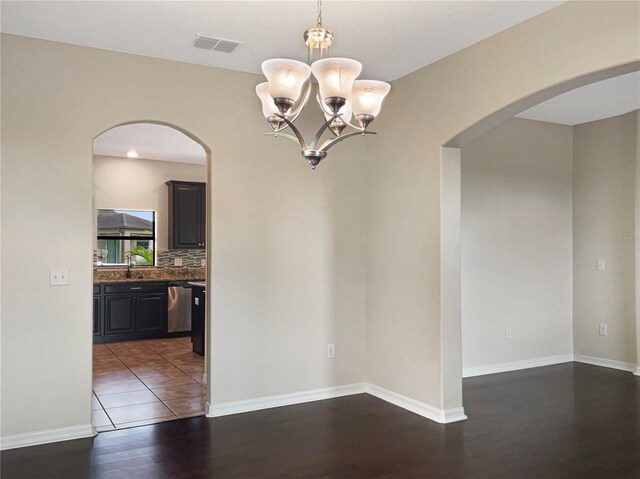 unfurnished dining area with an inviting chandelier and dark hardwood / wood-style floors