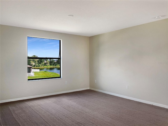 unfurnished room featuring carpet and a water view