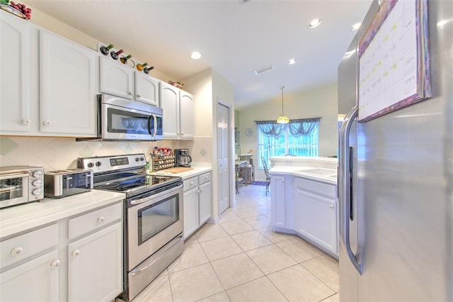 kitchen featuring decorative backsplash, vaulted ceiling, white cabinets, stainless steel appliances, and decorative light fixtures