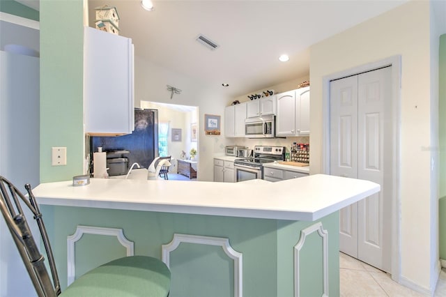 kitchen featuring a kitchen breakfast bar, kitchen peninsula, stainless steel appliances, and white cabinets