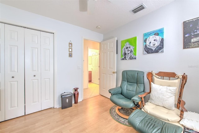 living area with light wood-type flooring, a textured ceiling, and ceiling fan