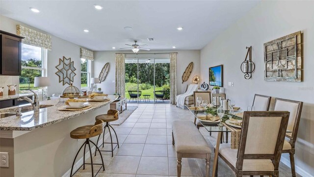 tiled dining room with a wealth of natural light, ceiling fan, and sink