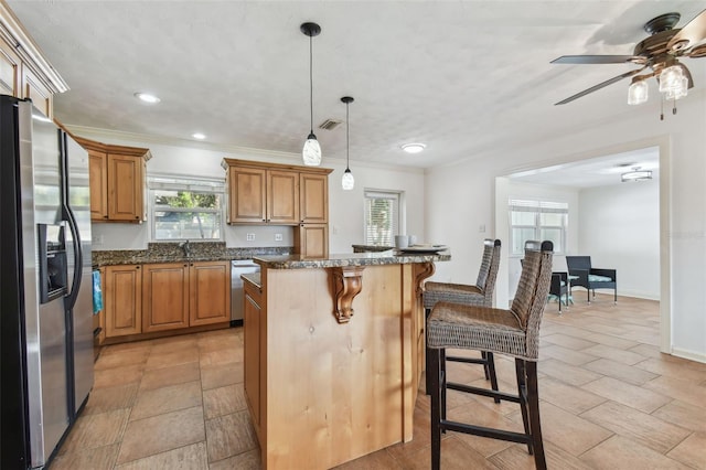 kitchen featuring a center island, hanging light fixtures, a breakfast bar area, dark stone countertops, and stainless steel appliances